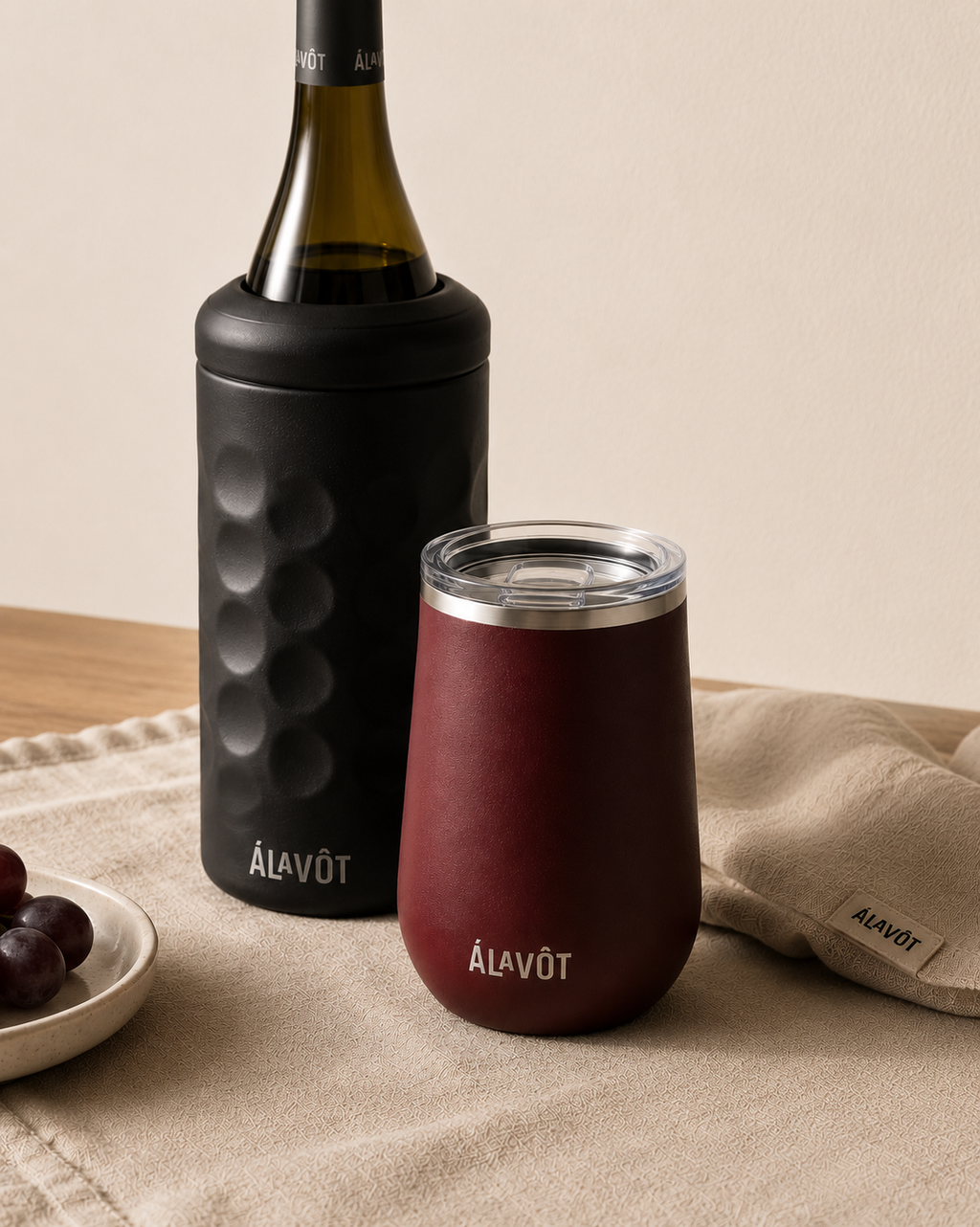 Black wine cooler bottle and insulted tumbler with 'Alavot' branding on a beige surface.