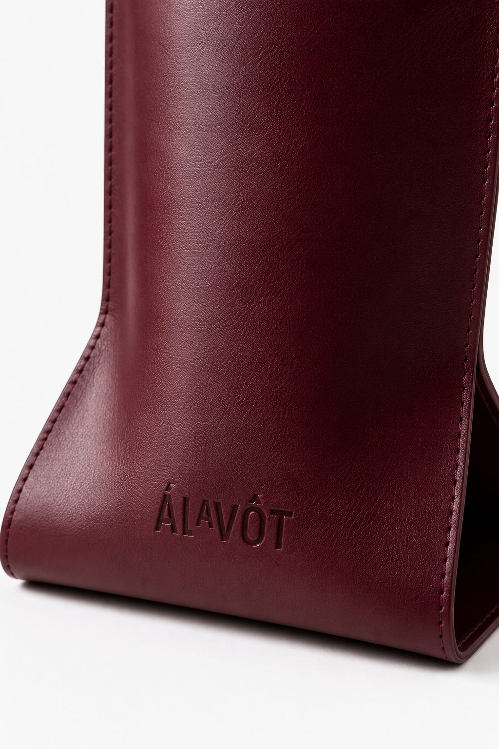 Close-up of a burgundy faux leather tote bag, wine bottle holder, gift bag  with 'ALAVOT' branding on a white background