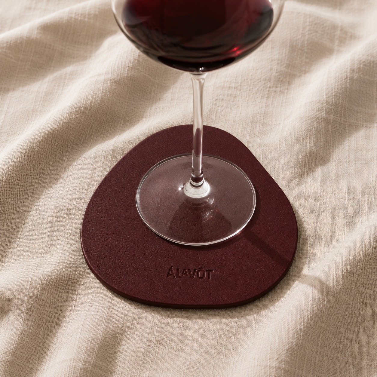 Faux leather coaster with alavot logo with red wine in a glass. 