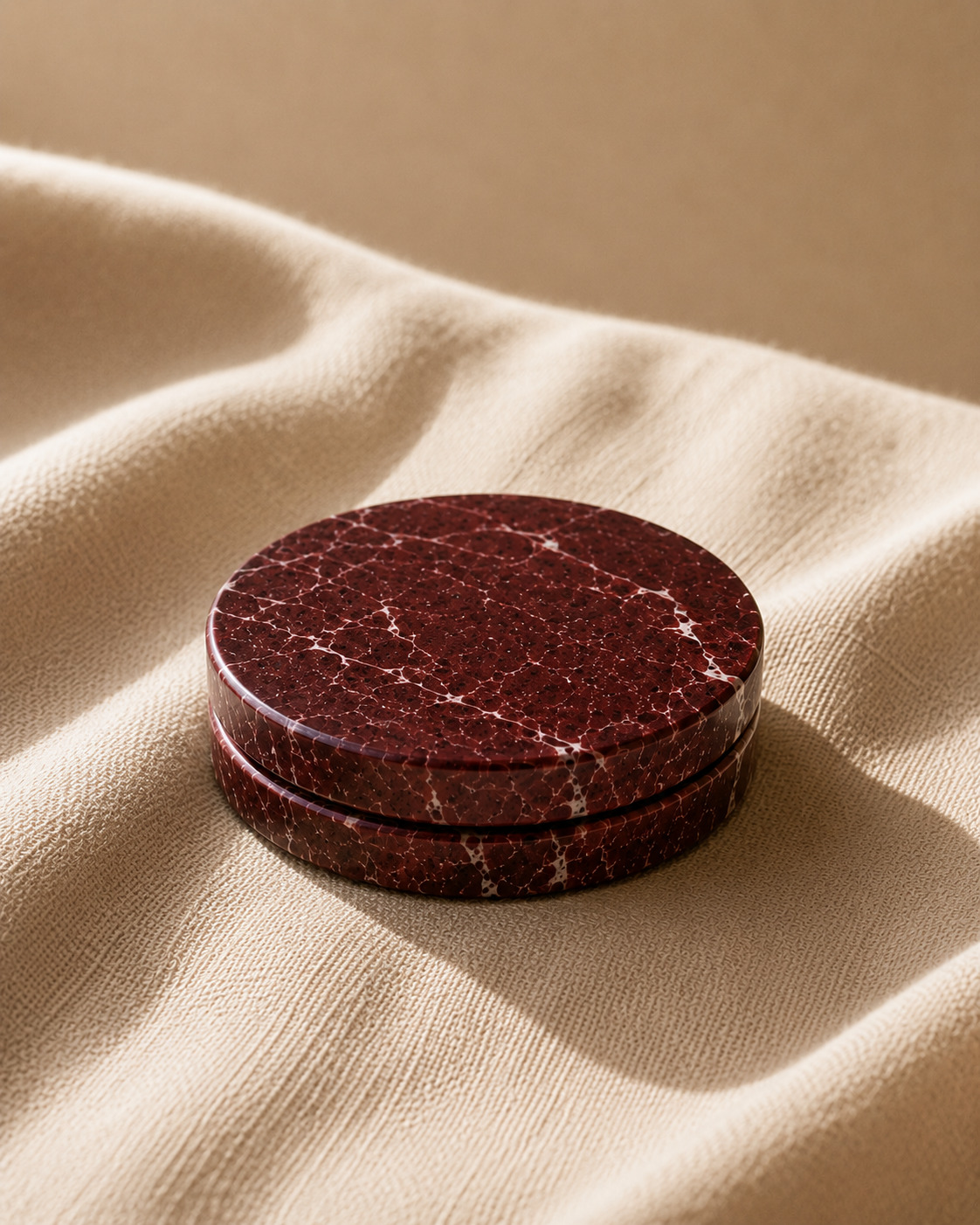 Red marble coaster on beige fabric