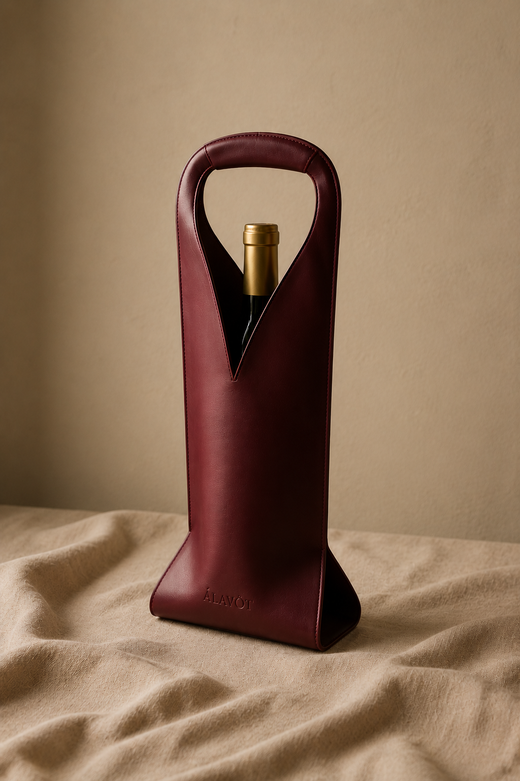Red wine faux leather bottle holder with a bottle of wine on a beige surface and background. 
