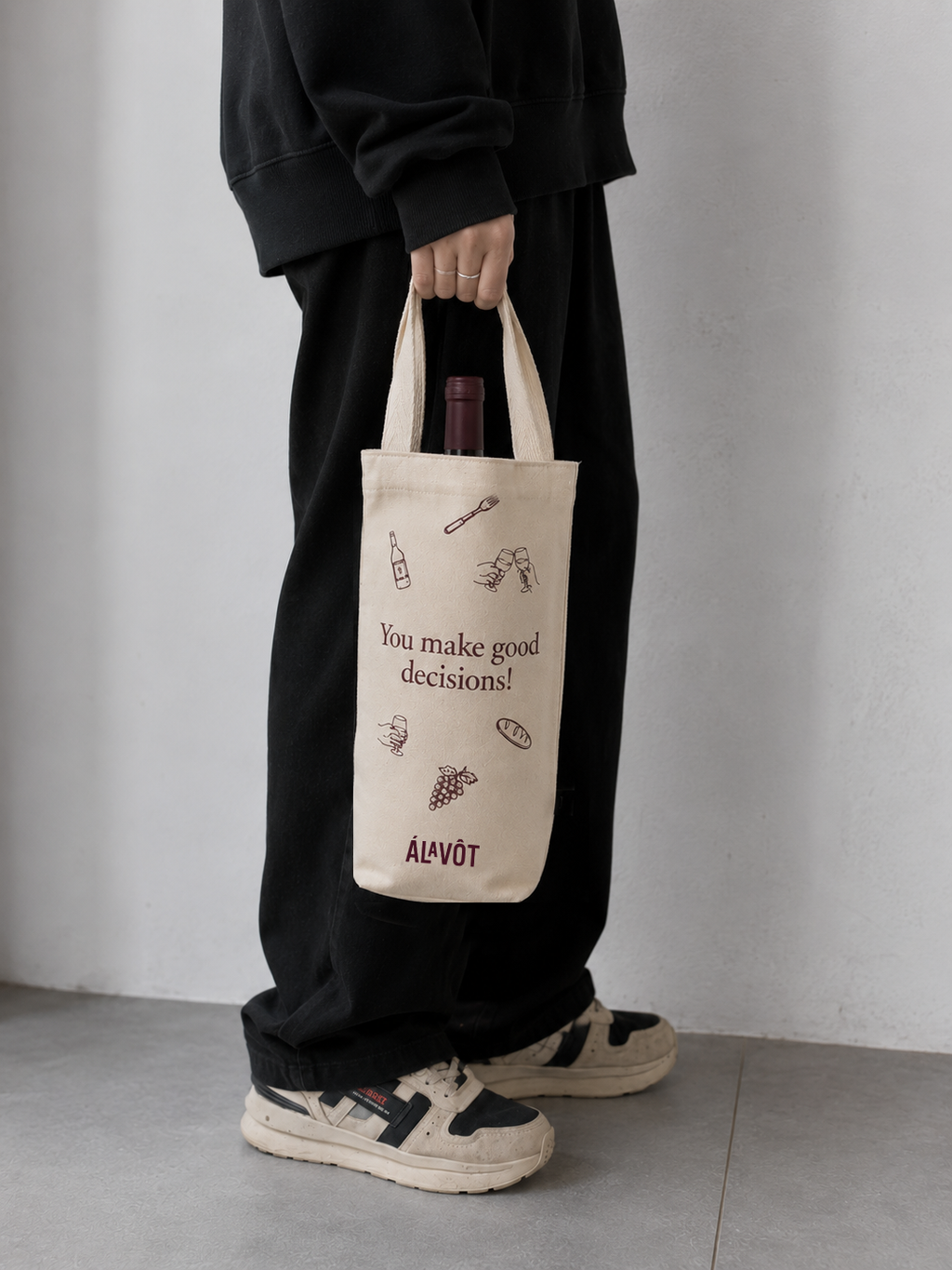 Person holding a tote bag with text and graphics, standing against a plain background