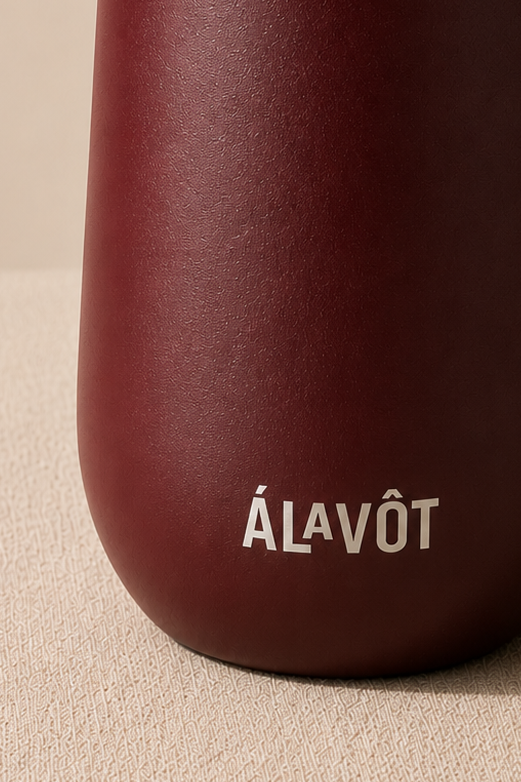 Maroon bottle with 'ÁLAVÔT' branding on a beige background