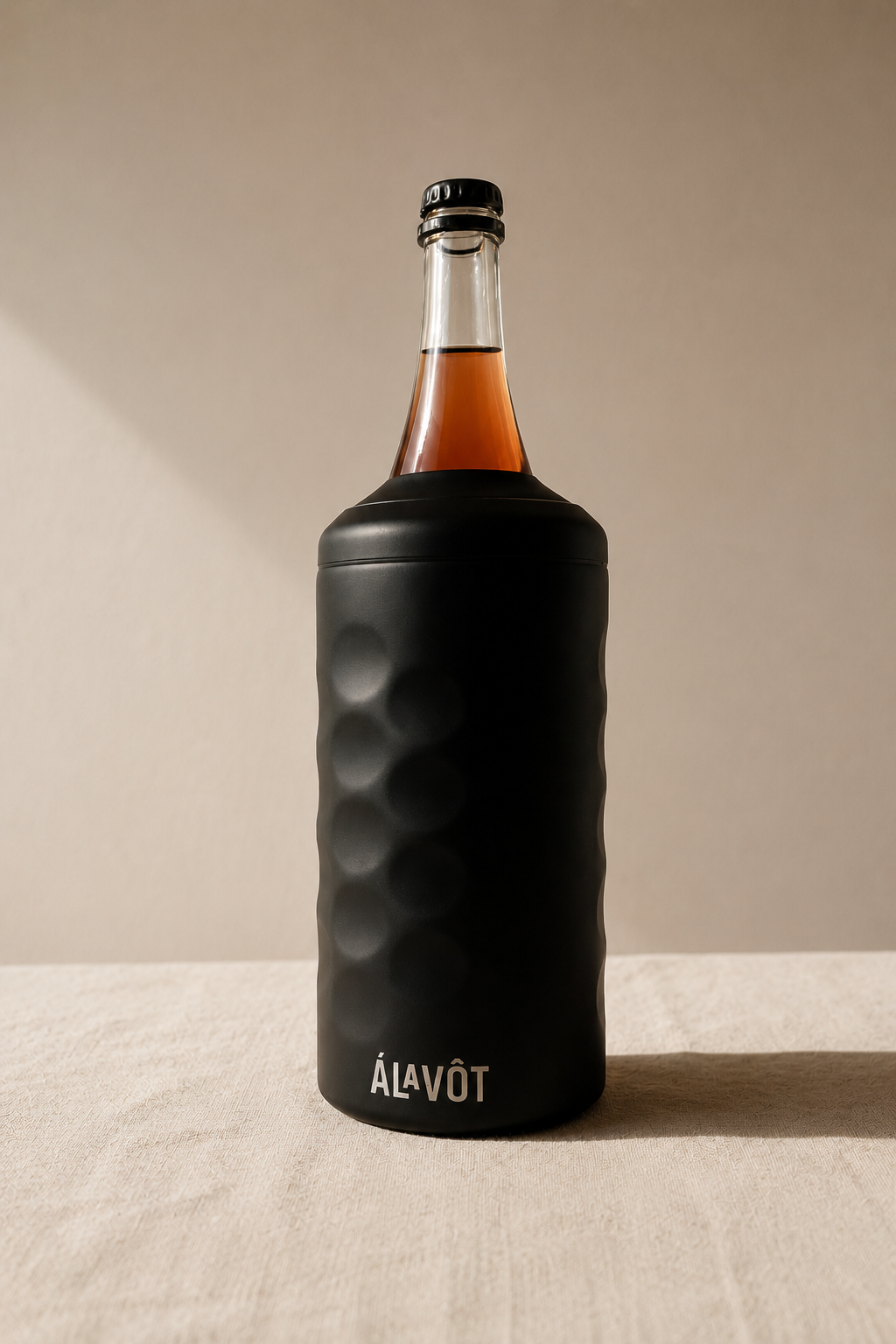 Bottle of Álavot with a black textured sleeve on a beige background