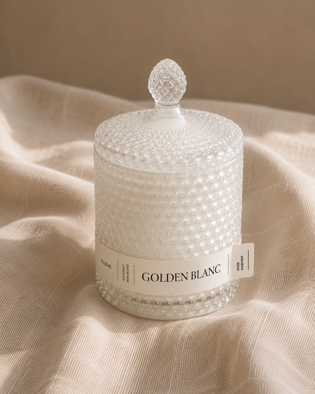 White textured candle labeled 'Golden Blanc' on a beige fabric background