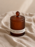 Scented Candle labeled 'Velvet Wine' with a textured brown lid on a beige fabric background. Alavot
